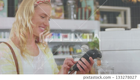 Processing payment woman using handheld terminal at cafe counter, with cash register and glass jars Processing payment woman using handheld terminal at cafe counter, with cash register and glass jars 133278027