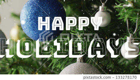 Displaying blue glitter bauble hanging on evergreen tree at home, with HAPPY HOLIDAYS, copy space Displaying blue glitter bauble hanging on evergreen tree at home, with HAPPY HOLIDAYS, copy space 133278170