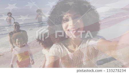 Taking woman in white top extending arm for selfie at sandy shoreline, with smartphone, flag motif Taking woman in white top extending arm for selfie at sandy shoreline, with smartphone, flag motif 133278234