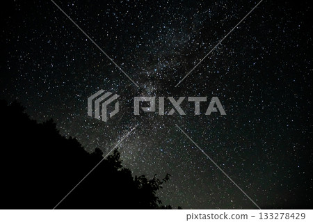 A fantastical landscape of mountain silhouettes and a starry sky with the Milky Way spreading across the night sky A fantastical landscape of mountain silhouettes and a starry sky with the Milky Way spreading across the night sky 133278429