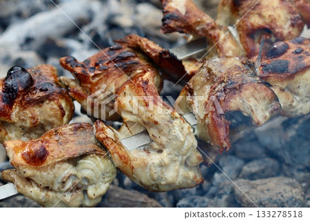 Grilled pieces of mackerel on skewers cooking over hot charcoal, with smoke rising. High quality photo Grilled pieces of mackerel on skewers cooking over hot charcoal, with smoke rising. High quality photo 133278518