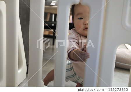 一個0歲的嬰兒透過嬰兒安全門好奇地看著我們。 一個0歲的嬰兒透過嬰兒安全門好奇地看著我們。 133278530