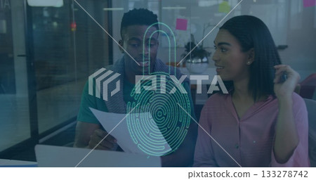 Colleagues in pink blouse and teal top reviewing documents in office, with digital security overlay Colleagues in pink blouse and teal top reviewing documents in office, with digital security overlay 133278742