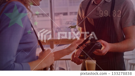 Tapping smartphone customer in blue top paying with handheld terminal at wooden counter with latte Tapping smartphone customer in blue top paying with handheld terminal at wooden counter with latte 133278838