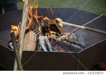 Campfire scene with bread being roasted over the flames, evoking warmth and nostalgia. Campfire scene with bread being roasted over the flames, evoking warmth and nostalgia. 133278873
