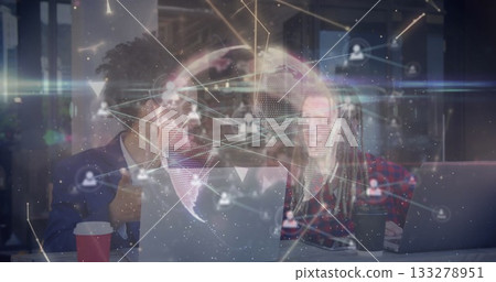 Collaborating coworkers wearing plaid and blazer reviewing network at office, with PCs, cups, globe 133278951