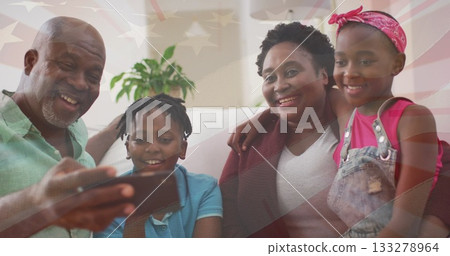 Gathering family members watching smartphone and leaning on light sofa in living room, with plant 133278964