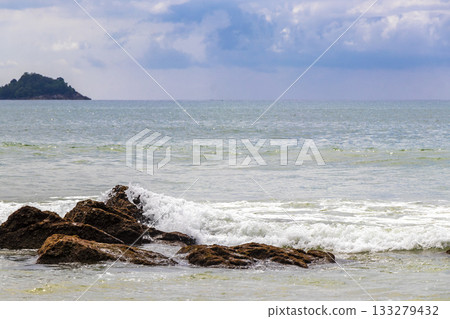 Rocky beach with rocks waves turquoise water in Patong Thailand. Rocky beach with rocks waves turquoise water in Patong Thailand. 133279432