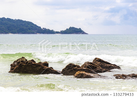 Rocky beach with rocks waves turquoise water in Patong Thailand. Rocky beach with rocks waves turquoise water in Patong Thailand. 133279433