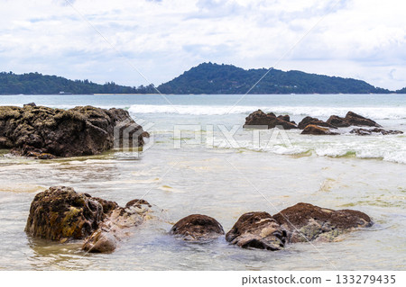 Rocky beach with rocks waves turquoise water in Patong Thailand. 133279435