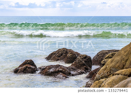 Rocky beach with rocks waves turquoise water in Patong Thailand. Rocky beach with rocks waves turquoise water in Patong Thailand. 133279441