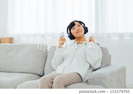 Woman listening to music while relaxing in her room 133279705