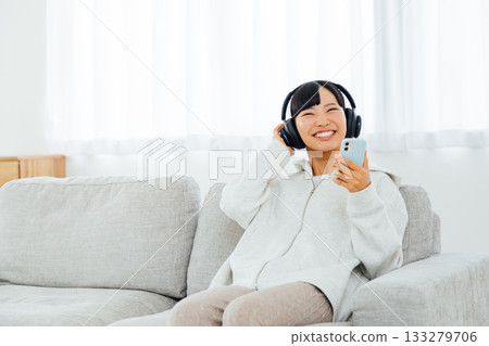 Woman listening to music while relaxing in her room 133279706