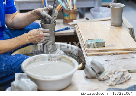 The rope craftsman is focused on making traditional pottery. The rope craftsman is focused on making traditional pottery. 133281064