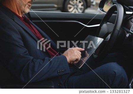 Businessman using glass digital tablet in van Businessman using glass digital tablet in van 133281327