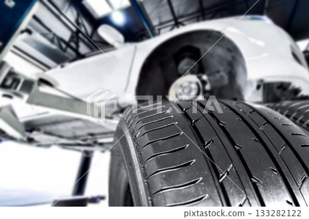 New tire treads ready for installation under a car on a lift 133282122