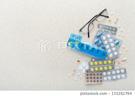 Medical background with copy-space of dosette box, pills and glasses on table flat lay 133282764