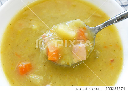 Vegetable and ham soup with potatoes, carrot, onion and leek in a white bowl.  133285274