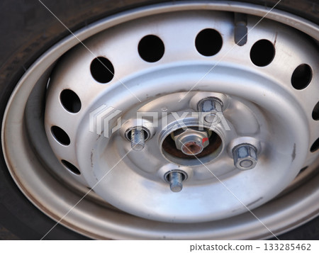 Tire on a 4-lug steel wheel with two nuts removed Tire on a 4-lug steel wheel with two nuts removed 133285462