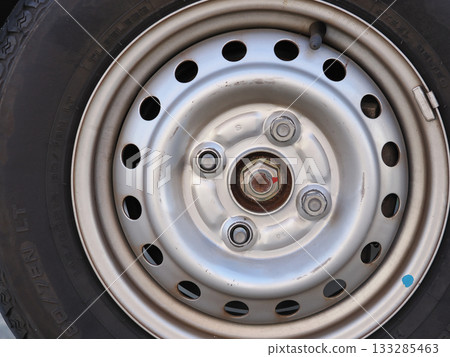 Tire on a 4-lug steel wheel with two nuts removed Tire on a 4-lug steel wheel with two nuts removed 133285463