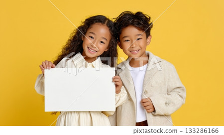 Smiling asian children holding blank sign on yellow background 133286166