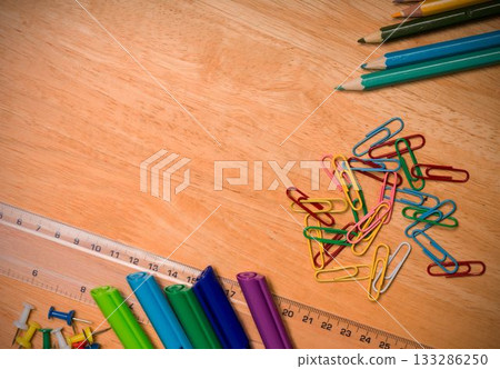 Flat design wooden tabletop is showing colorful paper clips, clear ruler, markers, pins and pencils Flat design wooden tabletop is showing colorful paper clips, clear ruler, markers, pins and pencils 133286250
