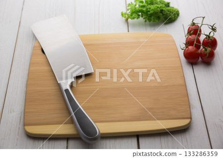 Knife on wooden chopping board with tomatoes and parsley 133286359