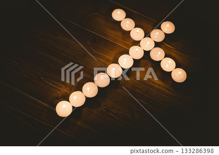Burning candles in shape of cross on table 133286398