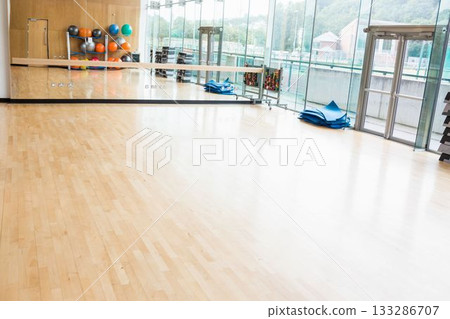 Flat design fitness studio is showing wood floor, mirrored wall, colorful balls, mats, copy space 133286707