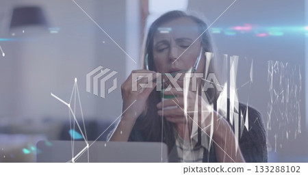 Sipping analyst in white blouse, cardigan, analyzing data on laptop at office desk, with green cup Sipping analyst in white blouse, cardigan, analyzing data on laptop at office desk, with green cup 133288102