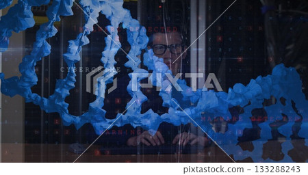 Analyzing man in dark sweater examining malware warning code at control room desk, blue chain links 133288243