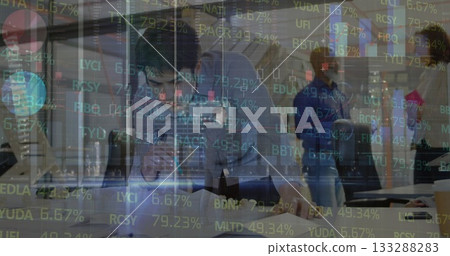 Analyst in blue shirt leaning over laptop in open office, with stock market data overlaying desks Analyst in blue shirt leaning over laptop in open office, with stock market data overlaying desks 133288283