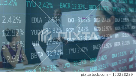 Presenting mature man in gray shirt standing beside projector screen showing charts in boardroom 133288289