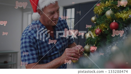 Man in Santa hat attaching gold bauble to Christmas tree at home, Joy overlays, copy space 133288474