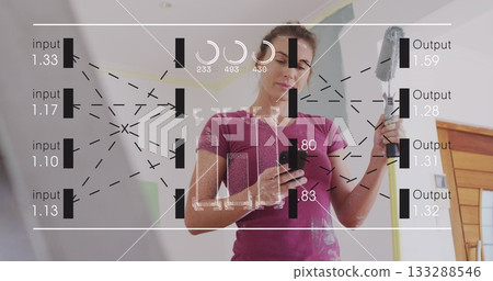 DIY painter wearing t-shirt holding smartphone and painting wall at home with long roller handle 133288546