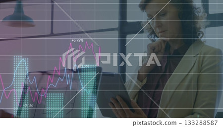 Analyzing mature businesswoman studying data on tablet in office, with chart overlay, copy space Analyzing mature businesswoman studying data on tablet in office, with chart overlay, copy space 133288587