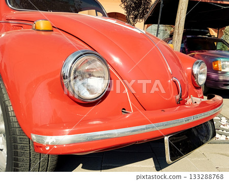 a detailed view of the hood and round headlight of a classic red car a detailed view of the hood and round headlight of a classic red car 133288768