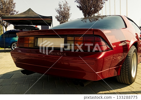 a rear view of a red classic sports coupe at an outdoor exhibition in sunny weather a rear view of a red classic sports coupe at an outdoor exhibition in sunny weather 133288775