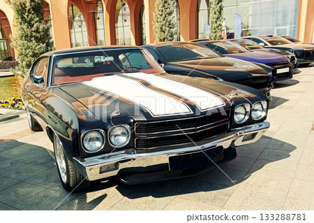 black classic muscle car with white stripes in a row at an exhibition 133288781