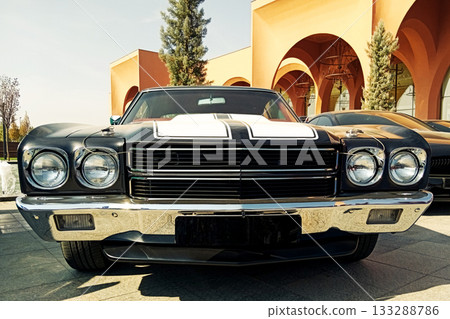 the front part of a black classic muscle car with white stripes and a chrome bumper the front part of a black classic muscle car with white stripes and a chrome bumper 133288786