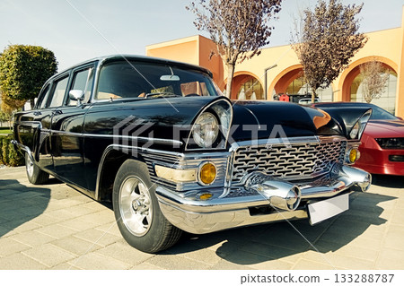 the front part of a luxurious black vintage automobile with chrome details at a summer exhibition 133288787