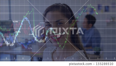 Smiling business casual White female sitting in open-plan office, with chart overlay and laptop 133289310