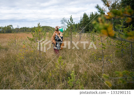 Woman cradling Magyar Vizsla dog in autumn field during hike with backpack, warm bonding with owner 133290131