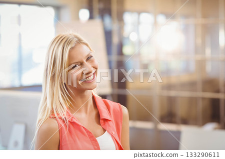 Female office professional standing and smiling in modern glass-walled office with flip chart 133290611