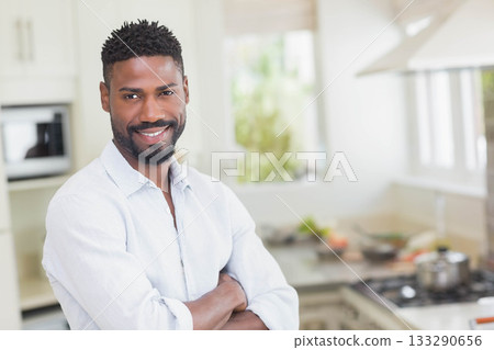 African American man smiling while standing in home kitchen at stove with cooking pot and microwave African American man smiling while standing in home kitchen at stove with cooking pot and microwave 133290656