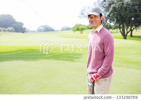 Asian man standing on golf green holding golf club, wearing cap and red glove, copy space Asian man standing on golf green holding golf club, wearing cap and red glove, copy space 133290709