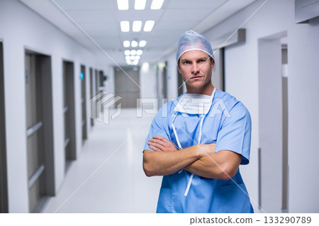 Male surgeon standing with arms crossed in hospital corridor wearing stethoscope, copy space Male surgeon standing with arms crossed in hospital corridor wearing stethoscope, copy space 133290789