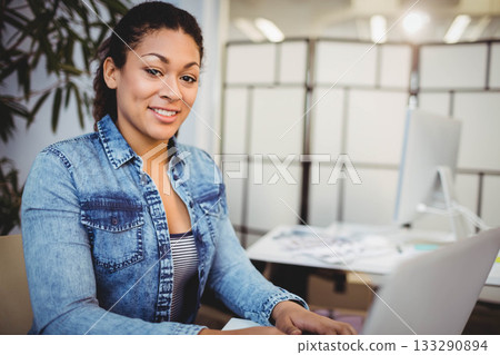 African American woman typing on laptop at office by computer monitor, papers, plant, copy space African American woman typing on laptop at office by computer monitor, papers, plant, copy space 133290894