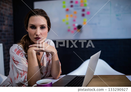 Woman in late twenties leaning over laptop at office with whiteboard with sticky notes, copy space Woman in late twenties leaning over laptop at office with whiteboard with sticky notes, copy space 133290927