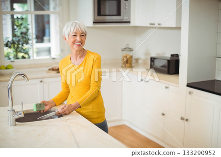 Senior woman washing glass dish with green sponge at home kitchen sink, copy space Senior woman washing glass dish with green sponge at home kitchen sink, copy space 133290952